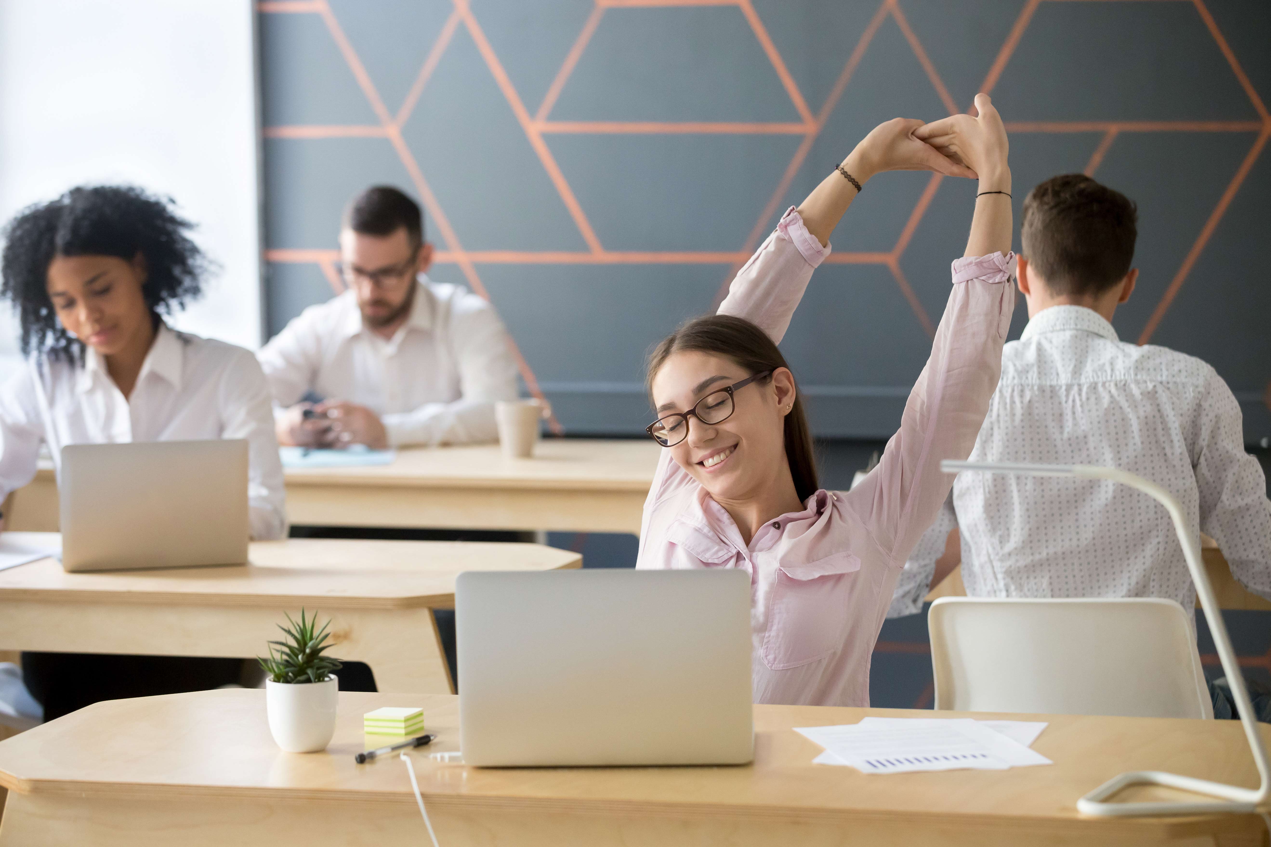 millennial employee stretching taking break from computer work relaxation